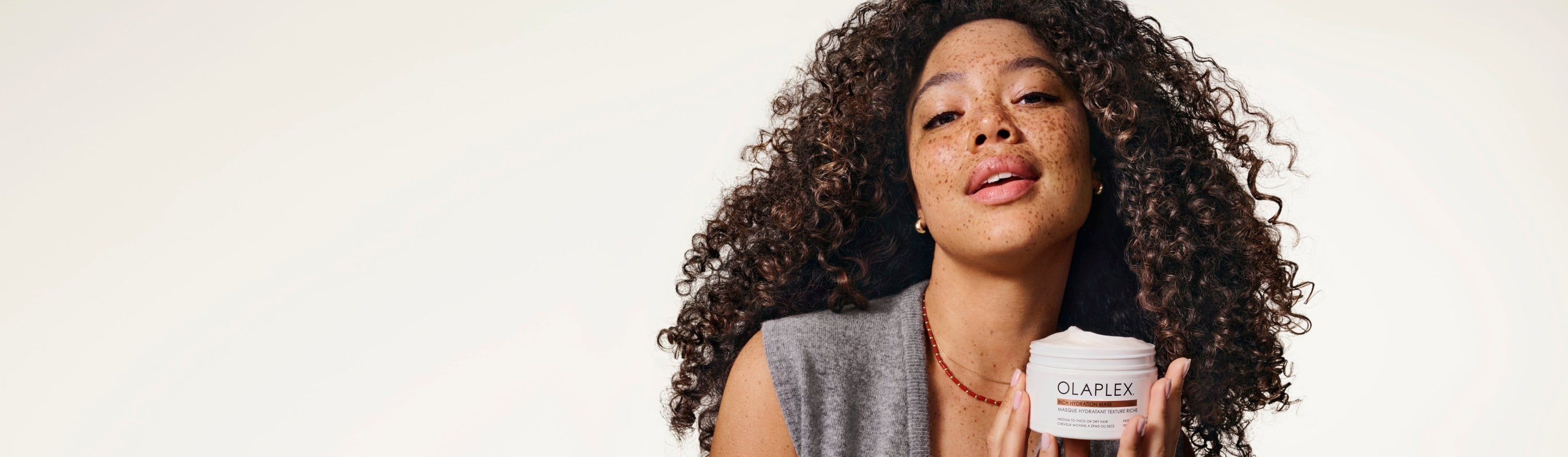Woman holding OLAPLEX’s  Rich Hydration Mask.