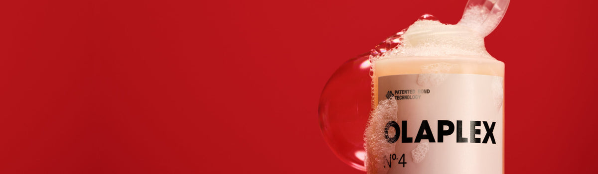 Red background with shampoo bottle in front with suds coming out the top