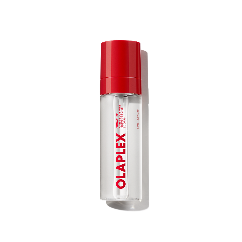 Una bottiglia trasparente di Olaplex Hair and Body Fragrance Mist con un vivace tappo rosso e il logo Olaplex ben visibile stampato verticalmente sul davanti, mostrata su uno sfondo a griglia trasparente. - main view