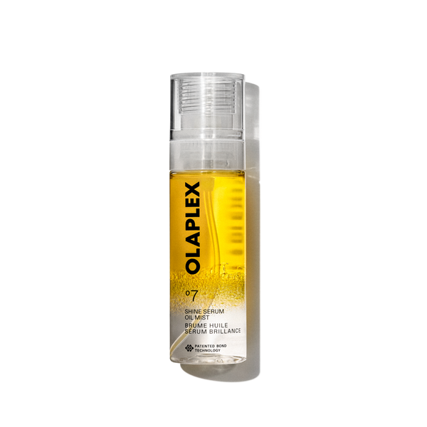 Una foto del prodotto Olaplex No. 7 Shine Serum Oil Mist in un flacone spray trasparente da 80 ml. Il flacone presenta un liquido giallo brillante visibile all'interno, un tappo trasparente e un'etichetta bianca pulita nella parte inferiore con testo nero che riporta il nome del prodotto, i dettagli e il caratteristico logo "No. 7". Il flacone è isolato su uno sfondo trasparente a griglia. - main view