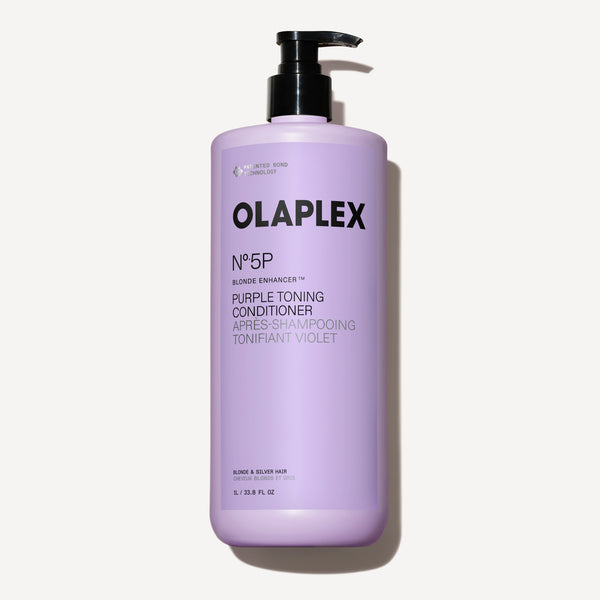 Un flacone da un litro di Olaplex No. 5P Purple Toning Conditioner con erogatore a pompa nero, posizionato al centro su uno sfondo a scacchi scuro. - main view